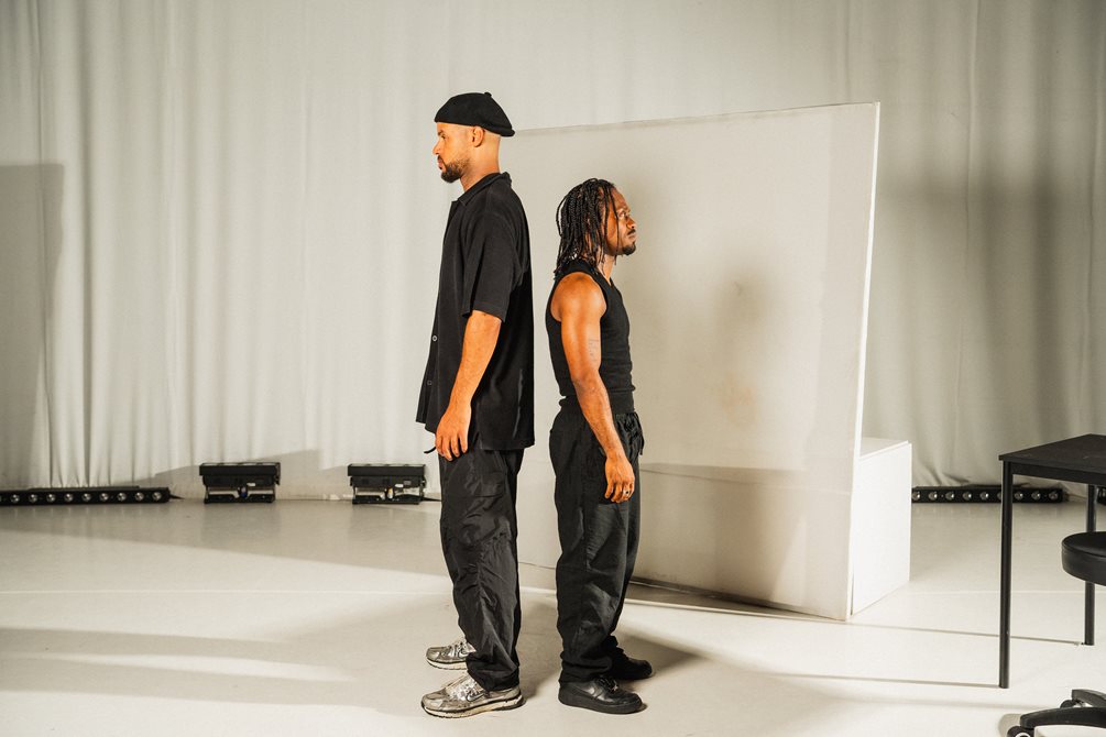 De to danserne står med ryggen mot hverandre.